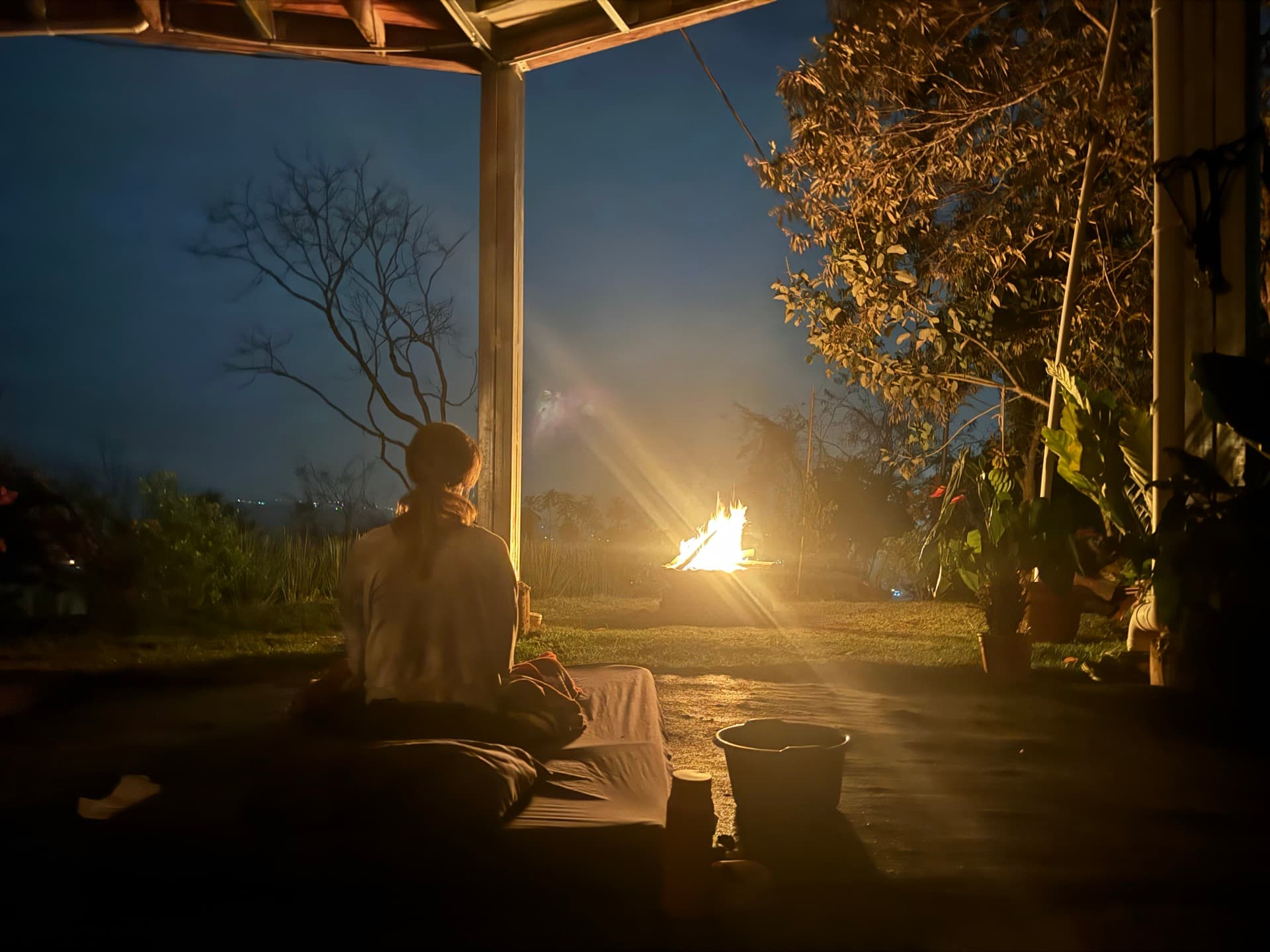 Person meditating by sacred fire at dusk